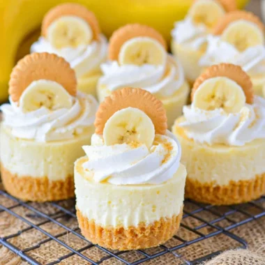 Mini banana pudding cheesecakes topped with whipped cream and banana slices