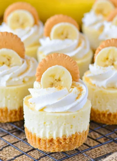 Mini banana pudding cheesecakes topped with whipped cream and banana slices