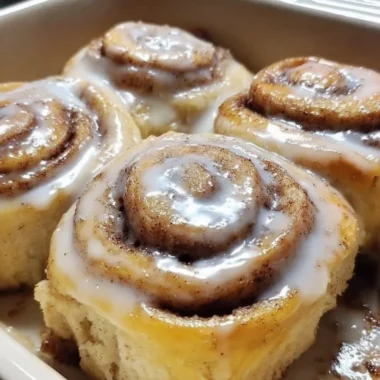 Delicious banana bread cinnamon rolls topped with icing on a rustic wooden table