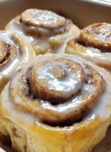 Delicious banana bread cinnamon rolls topped with icing on a rustic wooden table