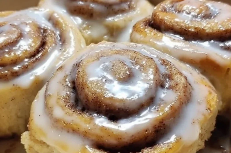 Delicious banana bread cinnamon rolls topped with icing on a rustic wooden table