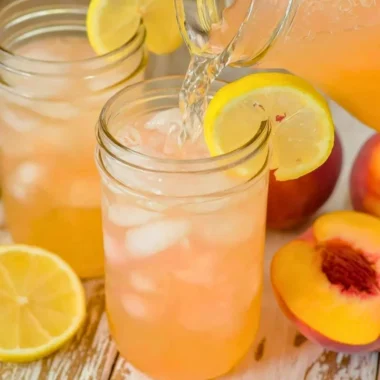 A refreshing glass of homemade peach lemonade with fresh peaches and lemon slices.
