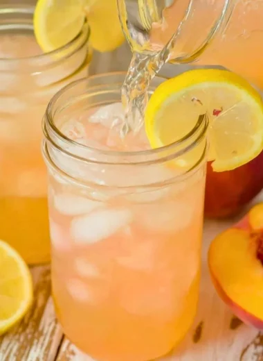 A refreshing glass of homemade peach lemonade with fresh peaches and lemon slices.