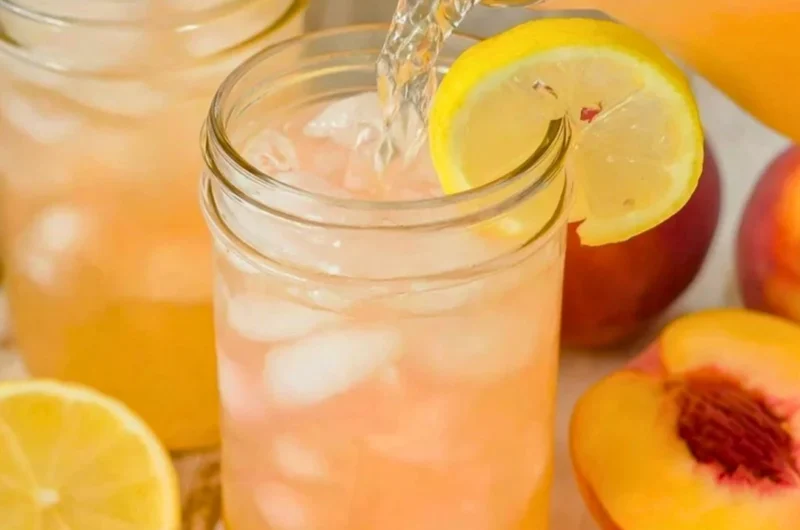 A refreshing glass of homemade peach lemonade with fresh peaches and lemon slices.