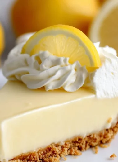 A slice of Magnolia Lemon Pie garnished with fresh lemon zest and mint leaves.