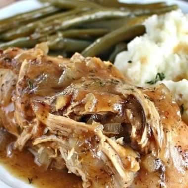 Crock Pot Mississippi Chicken served on a plate with herbs and sides