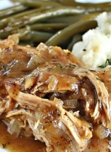 Crock Pot Mississippi Chicken served on a plate with herbs and sides