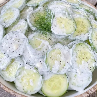 Cucumber Salad with mayo and sour cream in a bowl garnished with herbs