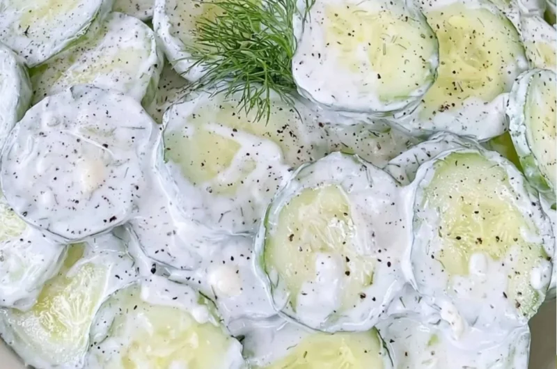 Cucumber Salad with mayo and sour cream in a bowl garnished with herbs