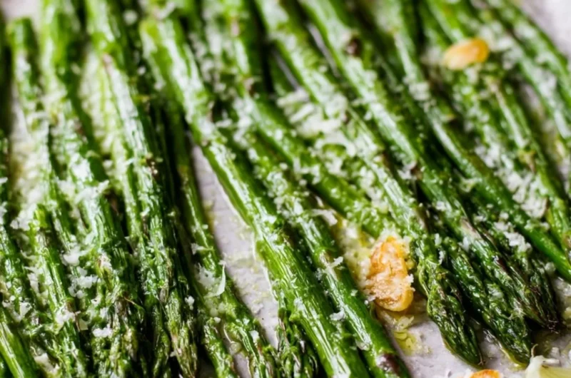 Oven roasted Garlic Parmesan asparagus on a plate garnished with parsley.