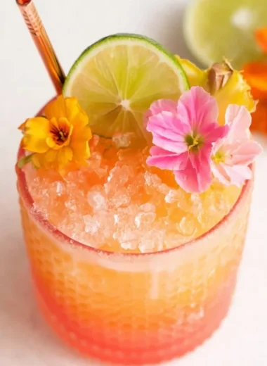 Colorful pineapple mango rum punch in a glass garnished with fruit