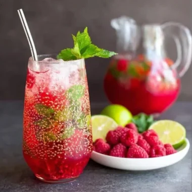 A refreshing Raspberry Mojito in a cocktail glass garnished with fresh raspberries and mint