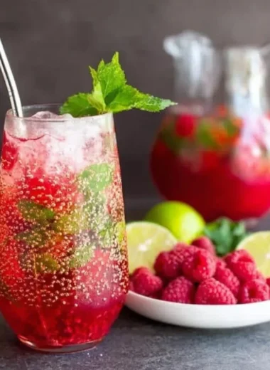 A refreshing Raspberry Mojito in a cocktail glass garnished with fresh raspberries and mint
