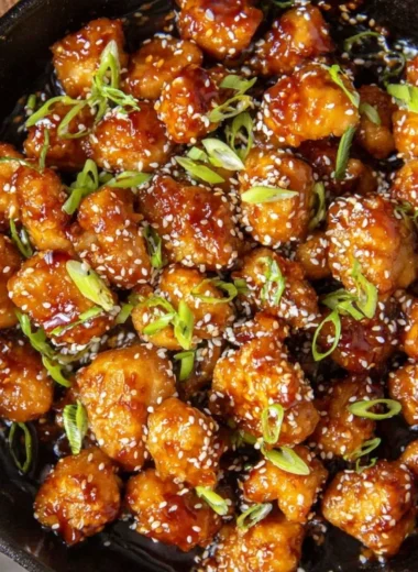 Delicious plate of sesame chicken garnished with sesame seeds and green onions