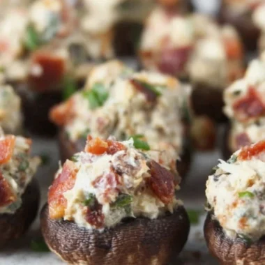 Stuffed mushrooms filled with bacon, cream cheese, and green onions on a serving platter.