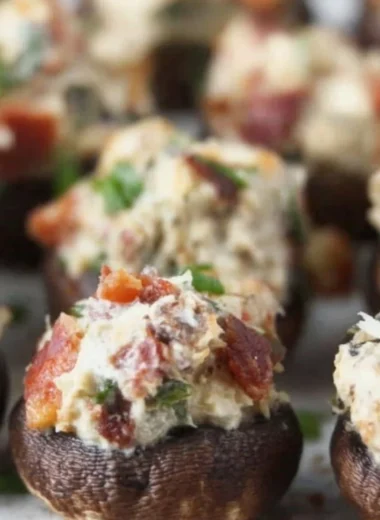 Stuffed mushrooms filled with bacon, cream cheese, and green onions on a serving platter.