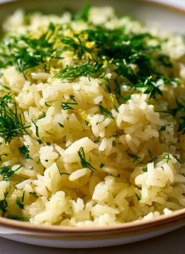 Authentic Greek lemon rice served in a bowl with fresh herbs and lemon slices.