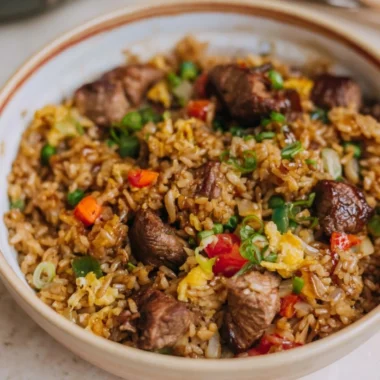 Delicious steak fried rice served in a bowl with colorful vegetables and herbs