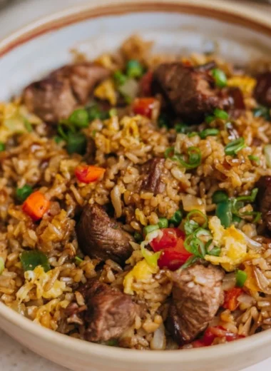 Delicious steak fried rice served in a bowl with colorful vegetables and herbs
