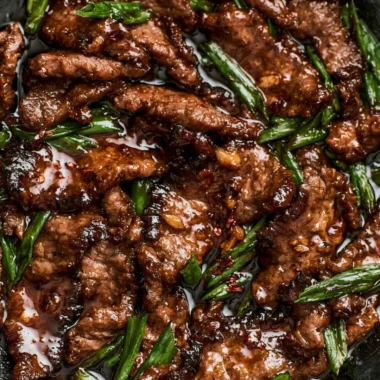 Delicious easy Mongolian beef served on a plate with green onions and rice.