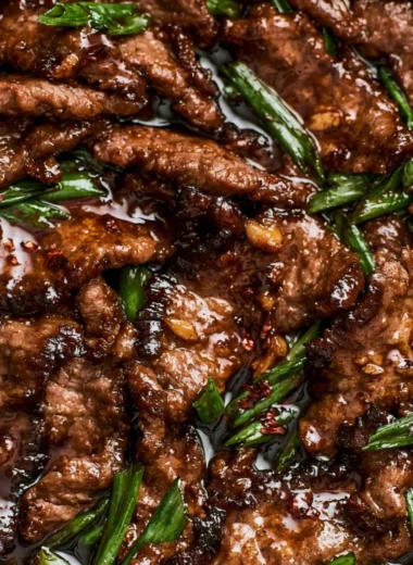 Delicious easy Mongolian beef served on a plate with green onions and rice.