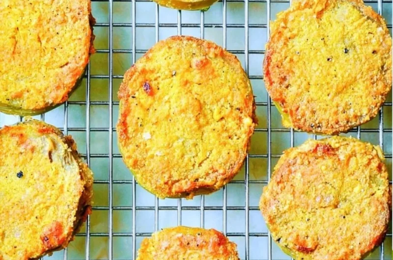 Plate of crispy, golden fried green tomatoes served with dipping sauce.