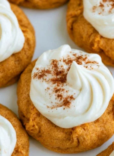 Pumpkin cookies with cream cheese frosting on a cooling rack