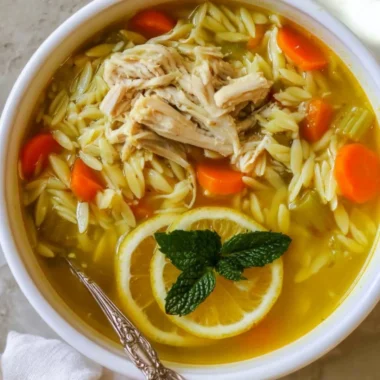 Bowl of Chicken Lemon Orzo Soup with fresh herbs and lemon slices