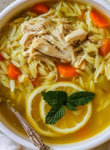 Bowl of Chicken Lemon Orzo Soup with fresh herbs and lemon slices