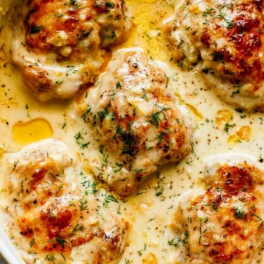 Creamy oven baked chicken thighs fresh from the oven, garnished and ready to serve.