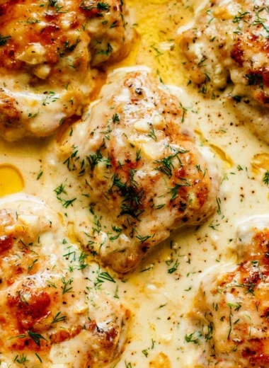 Creamy oven baked chicken thighs fresh from the oven, garnished and ready to serve.