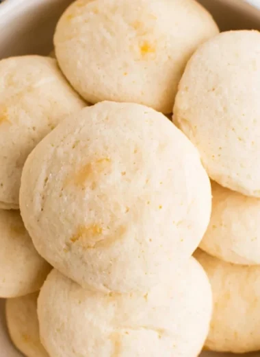 Freshly baked orange whipped shortbread cookies on a cooling rack