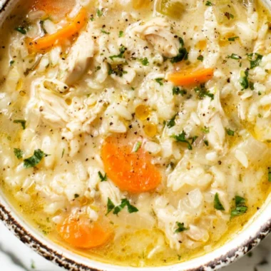 Bowl of simple chicken rice soup garnished with herbs