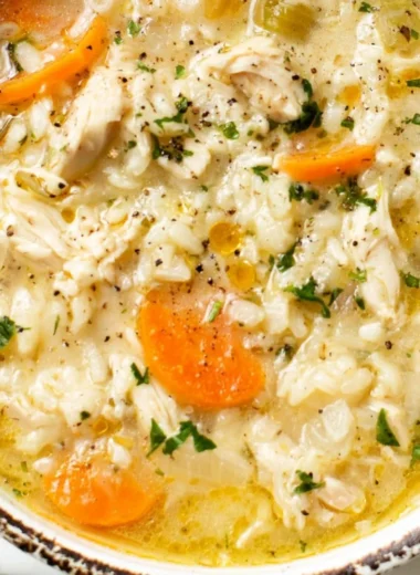 Bowl of simple chicken rice soup garnished with herbs