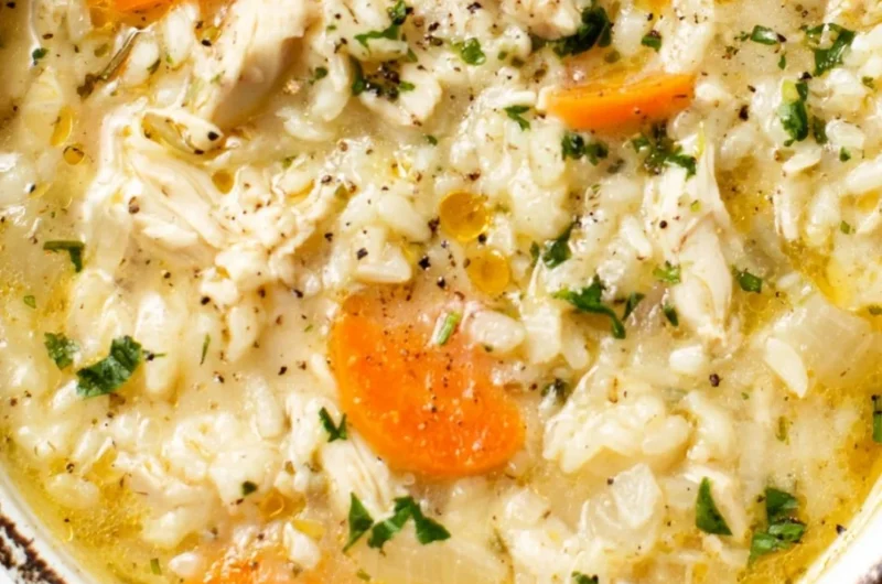 Bowl of simple chicken rice soup garnished with herbs